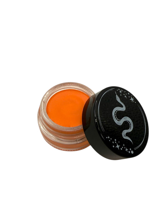 Open jar of orange cream eyeliner with black lid on a white background